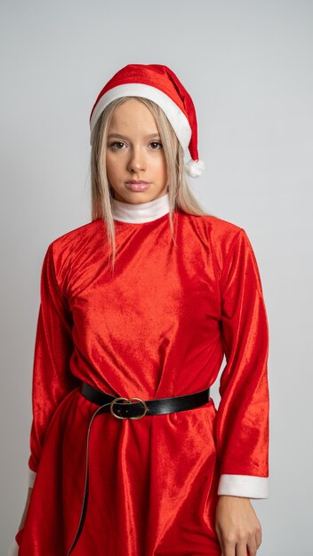 Joven mujer rubia posando en un traje de señorita Santa Claus en pared gris