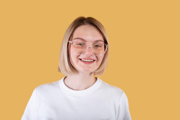 Joven mujer rubia sonriendo aislado en amarillo