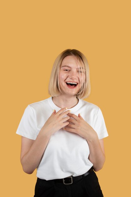 Joven mujer rubia sonriendo aislado en amarillo