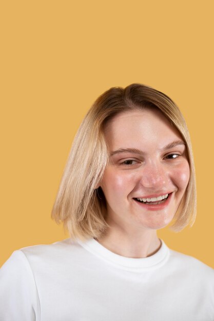 Joven mujer rubia sonriendo aislado en amarillo