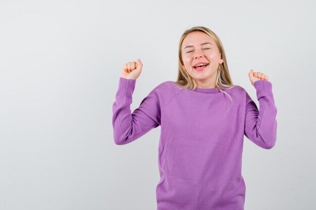 Joven mujer rubia con un suéter morado