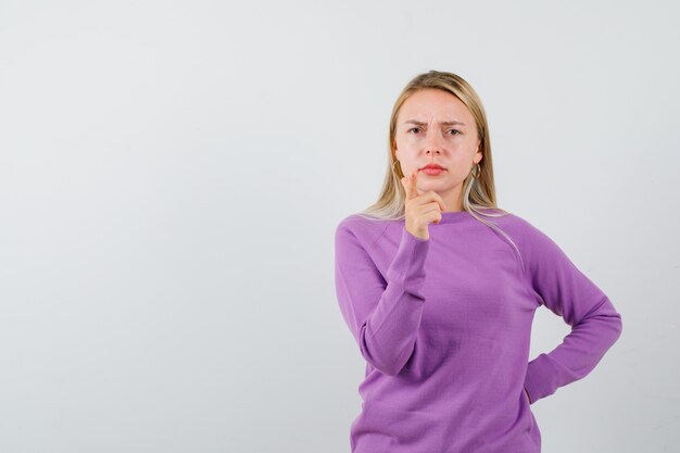 Joven mujer rubia con un suéter morado