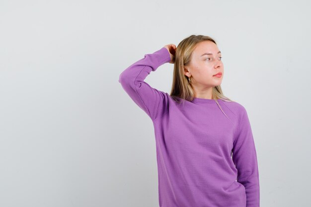 Joven mujer rubia con un suéter morado