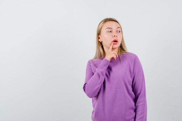 Joven mujer rubia con un suéter morado