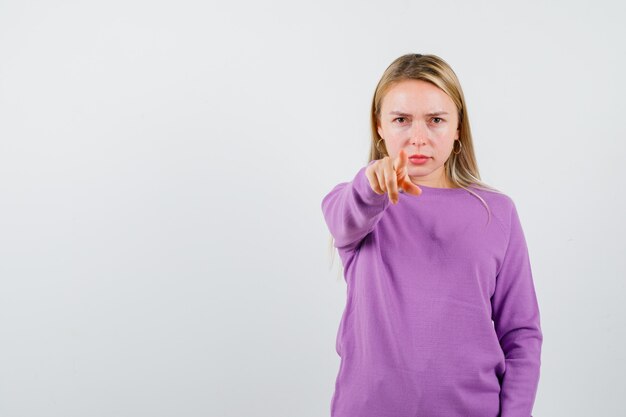 Joven mujer rubia con un suéter morado