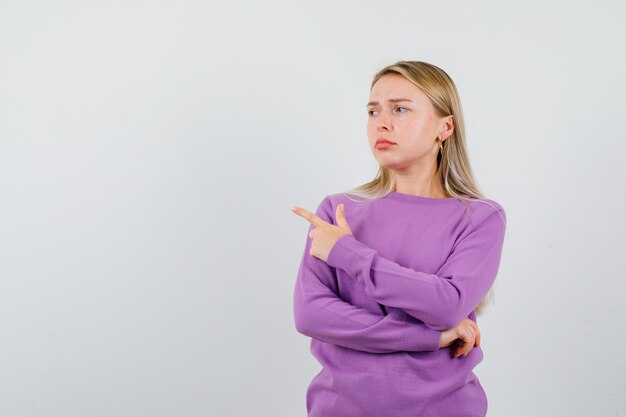 Joven mujer rubia con un suéter morado