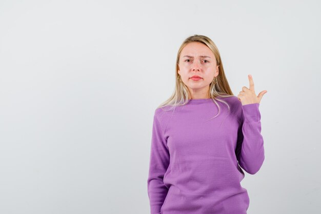 Joven mujer rubia con un suéter morado