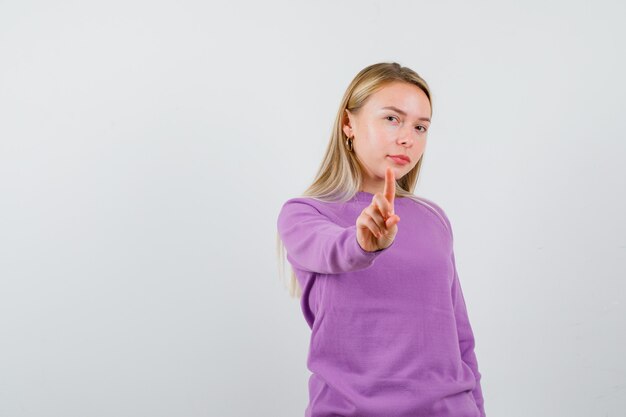 Joven mujer rubia con un suéter morado