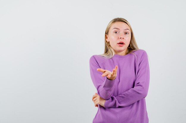 Joven mujer rubia con un suéter morado