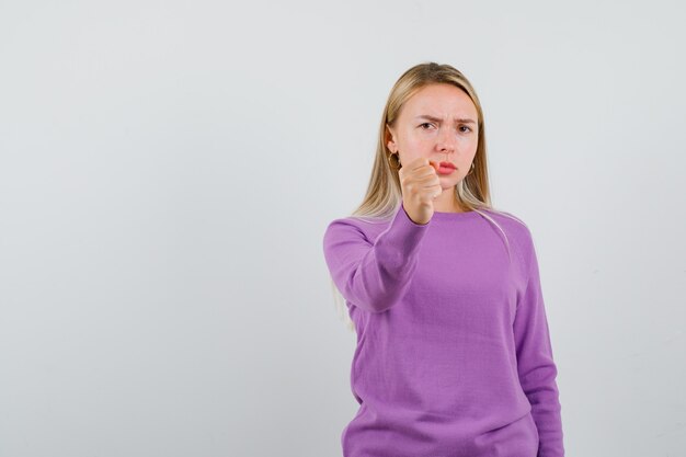 Joven mujer rubia con un suéter morado