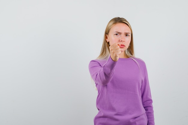 Joven mujer rubia con un suéter morado