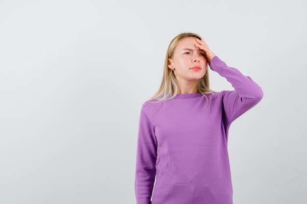 Joven mujer rubia con un suéter morado