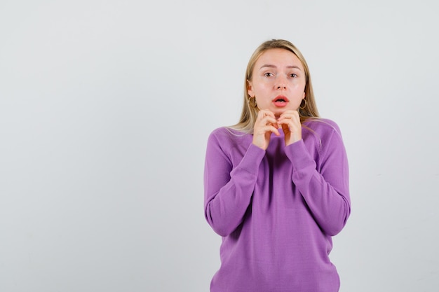 Joven mujer rubia con un suéter morado