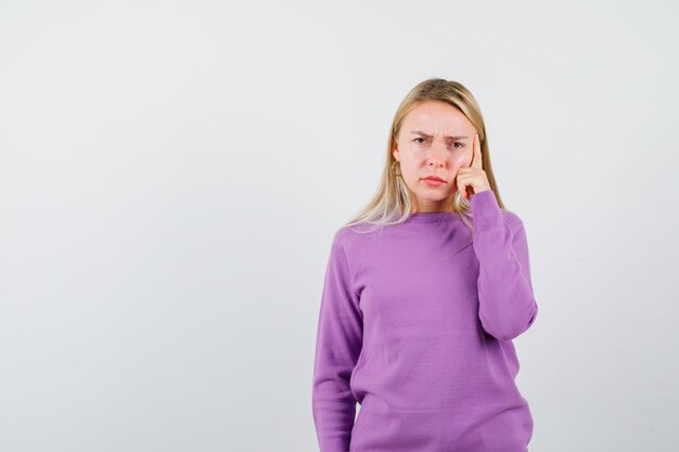 Joven mujer rubia con un suéter morado