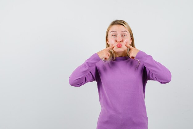 Joven mujer rubia con un suéter morado