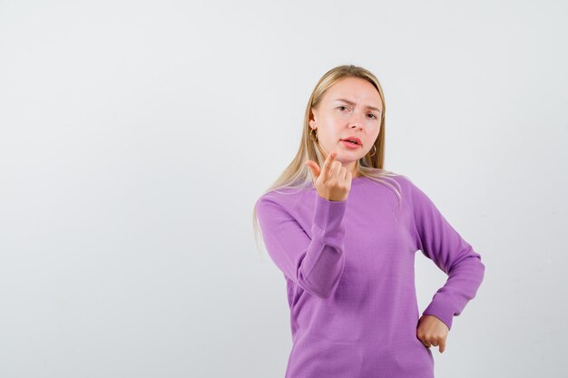 Joven mujer rubia con un suéter morado