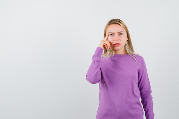 Joven mujer rubia con un suéter morado