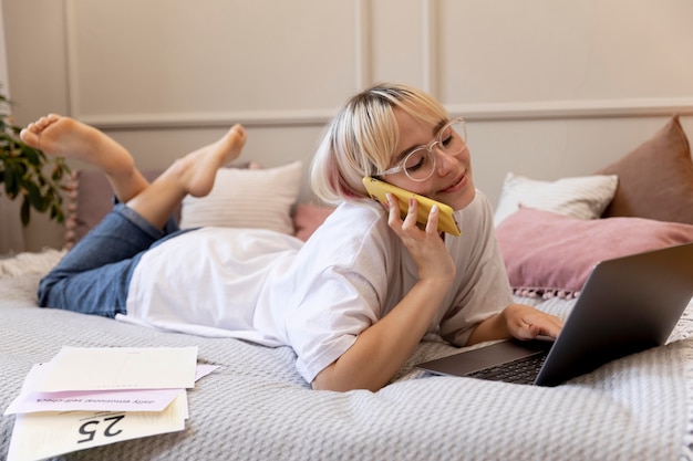 Joven mujer rubia trabajando desde casa en su cama