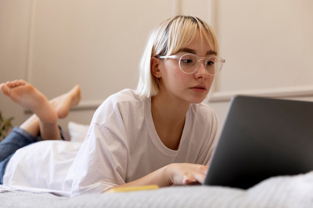 Joven mujer rubia trabajando desde casa en su cama