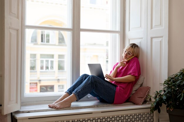 Joven mujer rubia trabajando desde casa en su computadora portátil