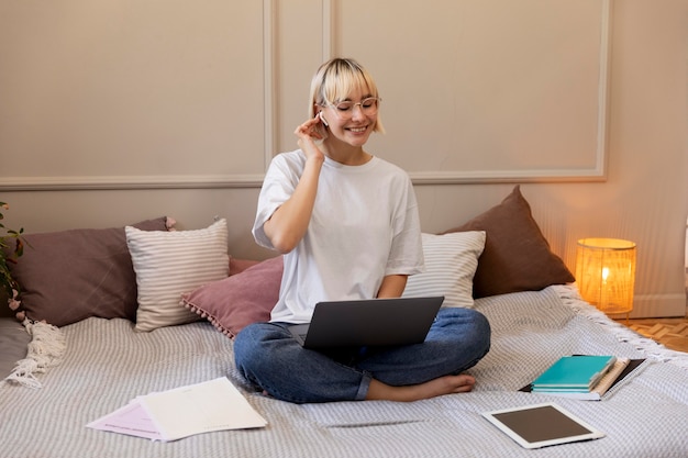 Foto gratuita joven mujer rubia trabajando desde casa en su computadora portátil