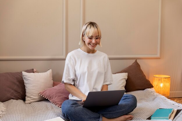 Joven mujer rubia trabajando desde casa en su computadora portátil