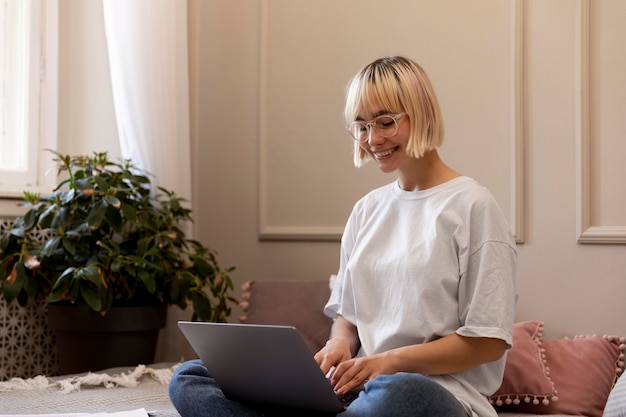 Joven mujer rubia trabajando desde casa en su computadora portátil