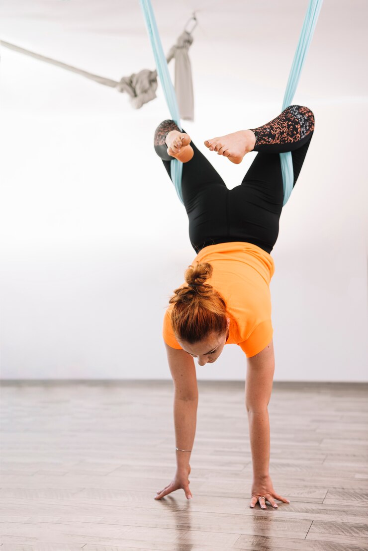 Foto gratuito joven mujer sana haciendo yoga antigravedad con hamaca azul