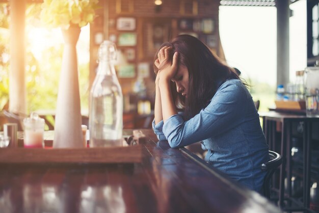 Joven mujer sentada en un café con su portátil, estresante para WOR