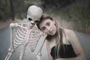 Foto gratuita joven mujer sentada en la carretera con esqueleto