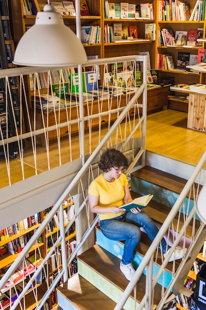 Joven mujer sentada en las escaleras con el libro