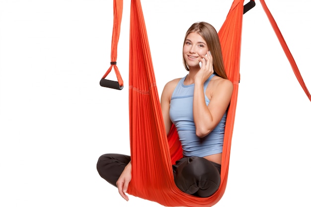 Joven mujer sentada en una hamaca para yoga aéreo antigravedad