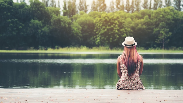 Foto gratuita joven mujer sentada en el muelle y mirando el río.