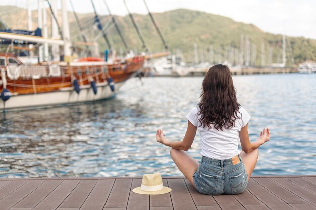 Joven mujer sentada en la orilla de un puerto