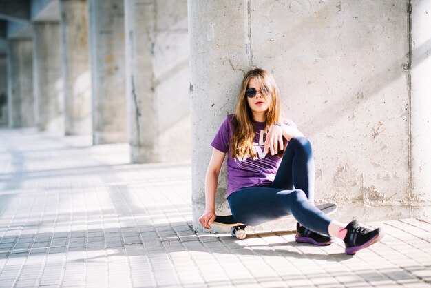 Joven mujer sentada en patineta