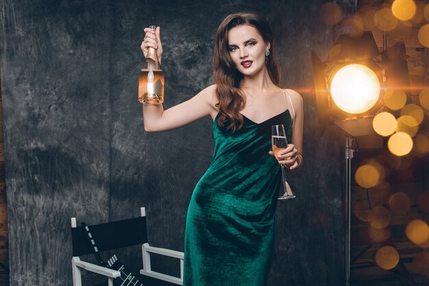 Joven mujer sexy con estilo en el cine entre bastidores, celebrando con una copa de champán