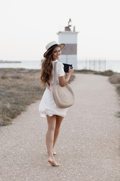 joven mujer sonriente con cámara de fotos cerca del mar