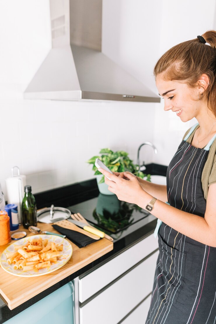 Foto gratuito joven mujer sonriente fotografiando la pasta rigatoni en el plato con teléfono celular