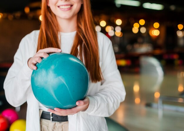 Joven mujer sosteniendo una bola de boliche turquesa