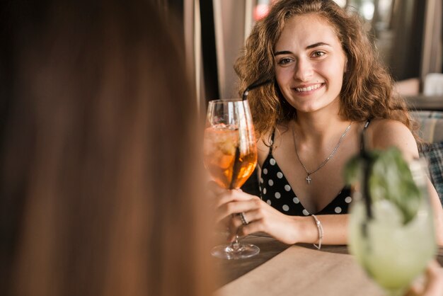 Joven mujer sosteniendo un cóctel con su amigo