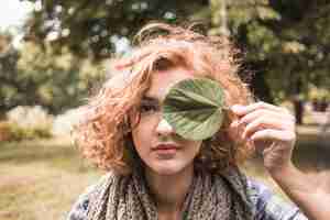 Foto gratuita joven mujer sosteniendo la hoja cerca del ojo