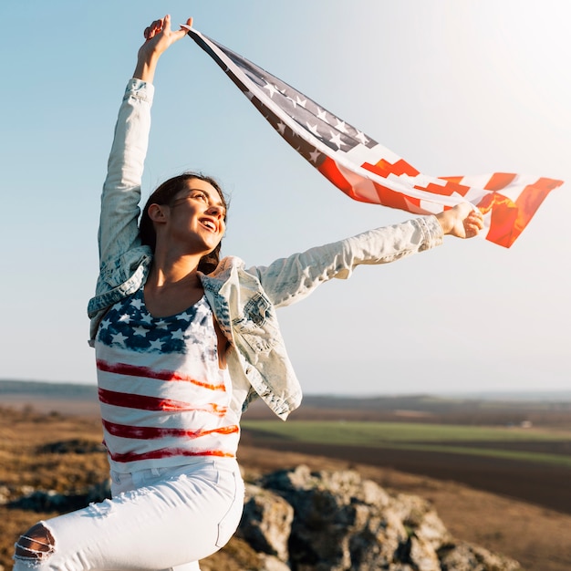 Foto gratuita joven mujer sosteniendo ondeando la bandera de américa