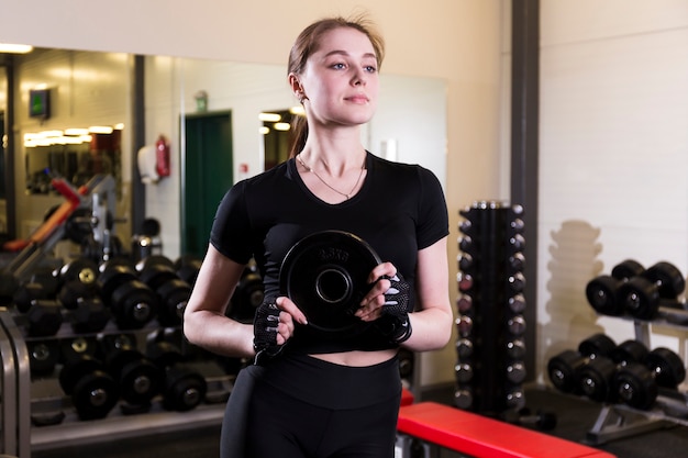 Joven mujer sosteniendo peso en gimnasio