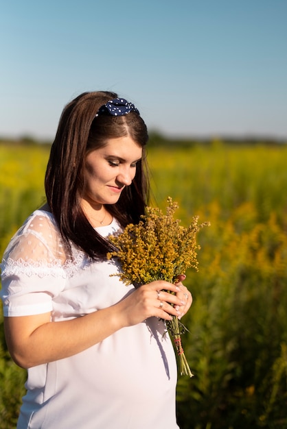 Foto gratuita joven mujer sosteniendo un ramo de flores en la naturaleza