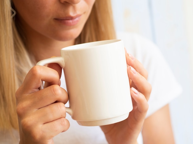 Foto gratuita joven mujer sosteniendo una taza blanca