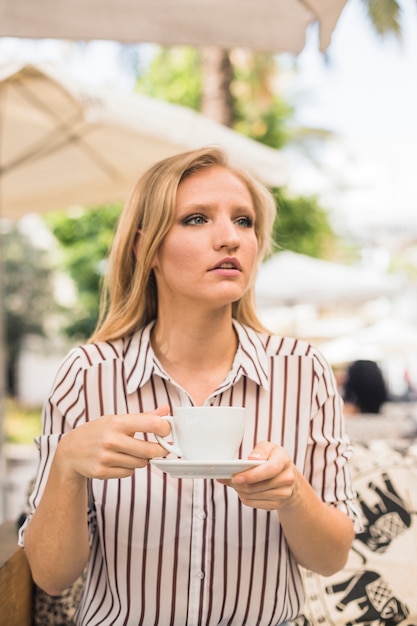 Joven mujer sosteniendo una taza de café mirando a otro lado