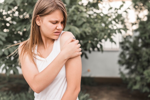 Joven mujer teniendo dolor en el hombro