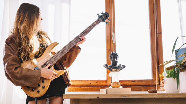 Joven mujer tocando la guitarra en casa