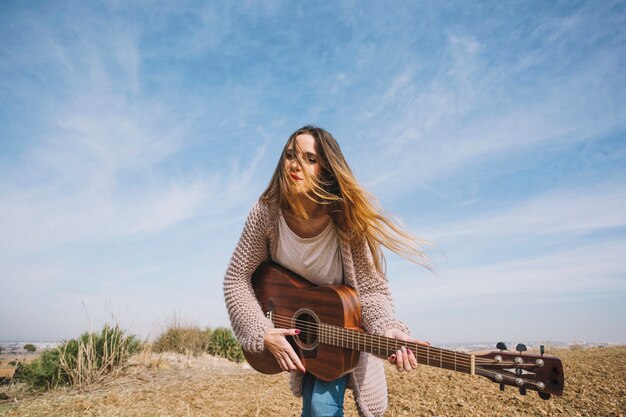 Joven mujer tocando la guitarra en la naturaleza