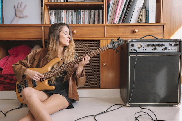 Joven mujer tocando la guitarra en el piso